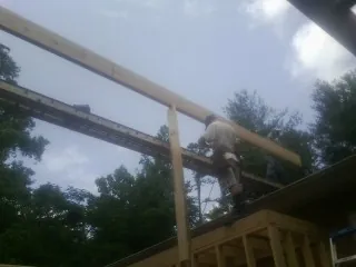 Carpenter setting a ridge beam over a new addition frame — Ice Dam Removal by Roofing Brothers in Stockholm