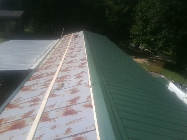 Old rusted panels beside newly installed green metal roofing — Wind Damage Roof Repair by Roofing Brothers in Stockholm