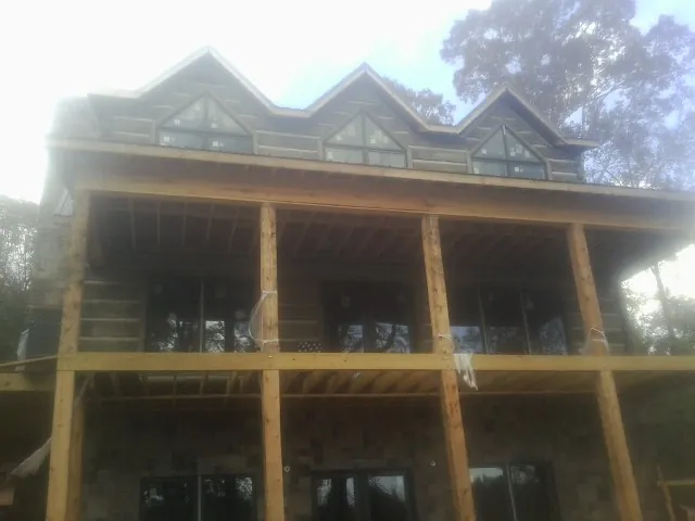 Dormers and porch framing on a large log home under construction — Roof Coating work by our crew in Stockholm