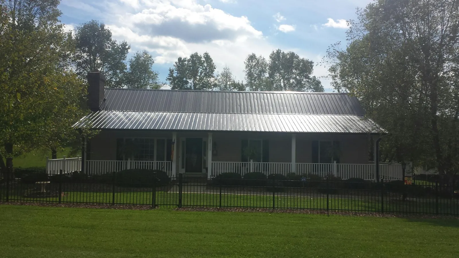 Gray metal roof on a brick ranch with a full width front porch — Gutter Guard Installation work by our crew in Stockholm