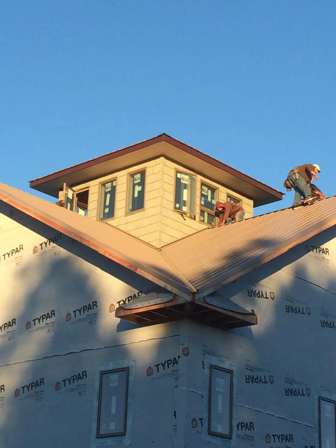 Roofers working around a rooftop cupola on a new metal roof at sunset — Roof Waterproofing in Stockholm by Roofing Brothers